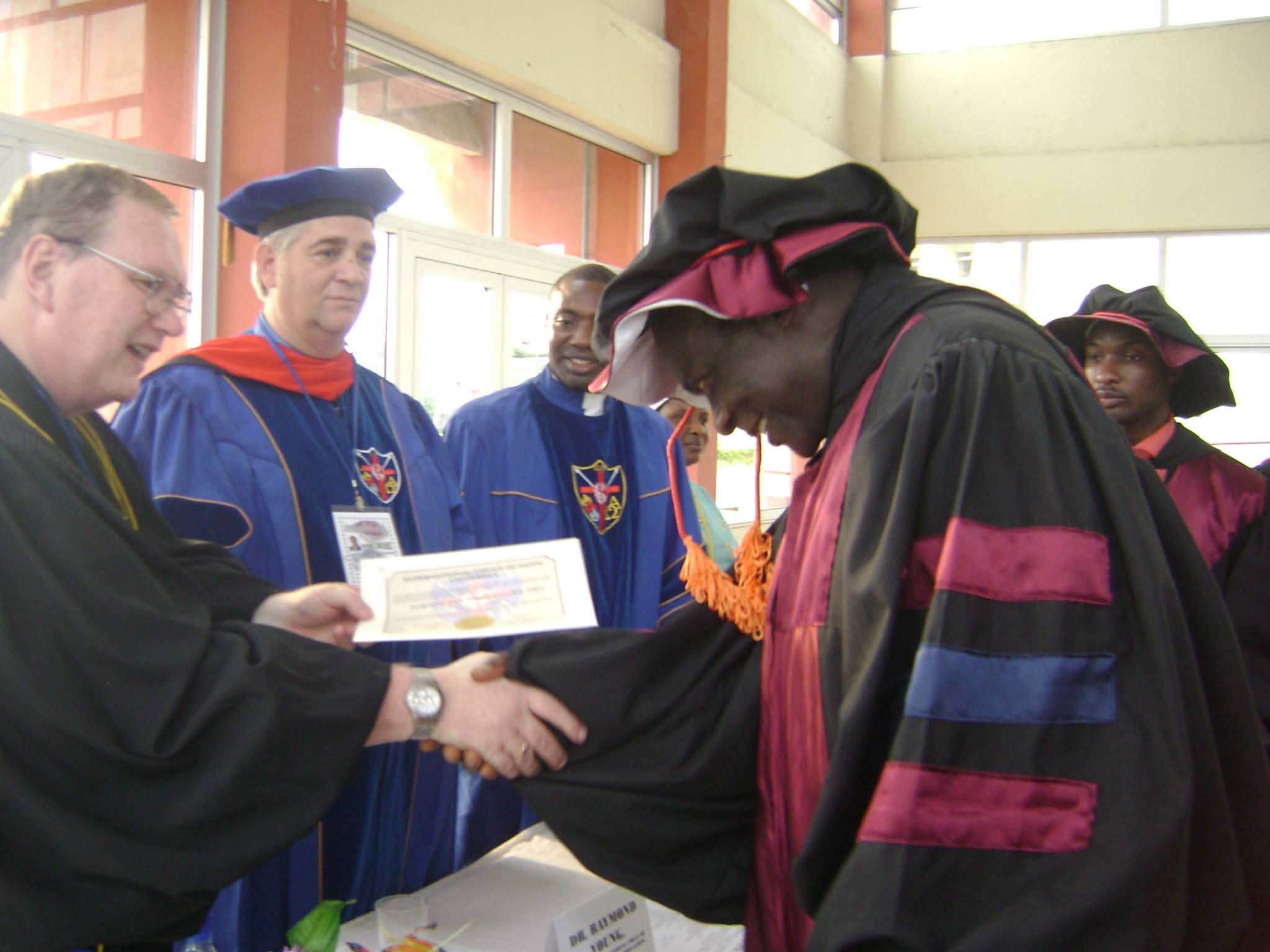 A graduand of ICOF Global University receiving their certificate and shaking hands at the congregation
